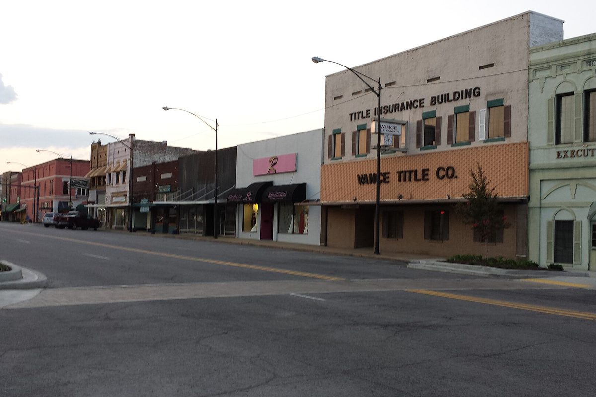Downtown Russellville's main street at dusk, with a row of older storefronts and the Title Insurance Building housing Vance Title Co. on the corner