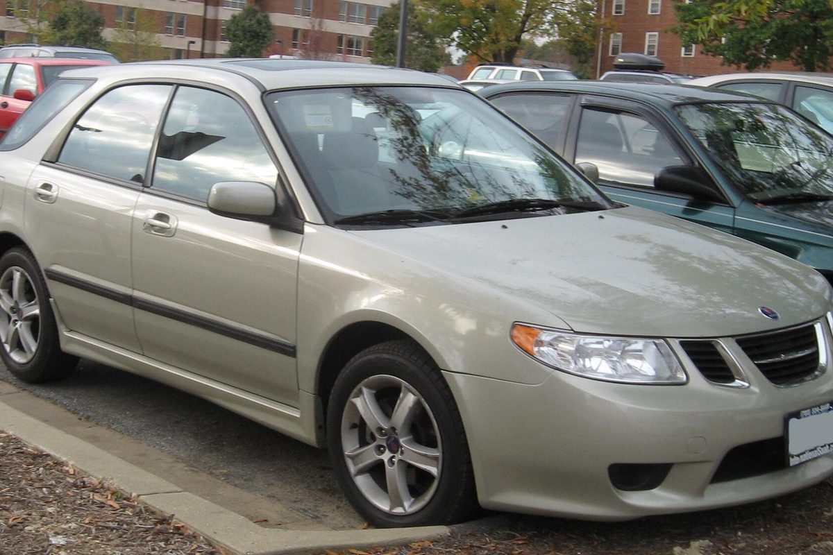 A champagne-colored Saab 9-2X wagon parked at a curb in front of brick apartment buildings
