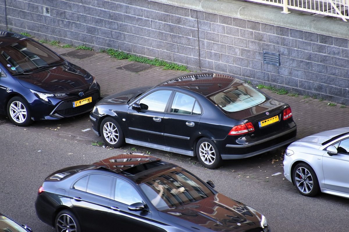 Black Saab 9-3 sport sedans parked along a curb beside a gray stone wall, seen from above