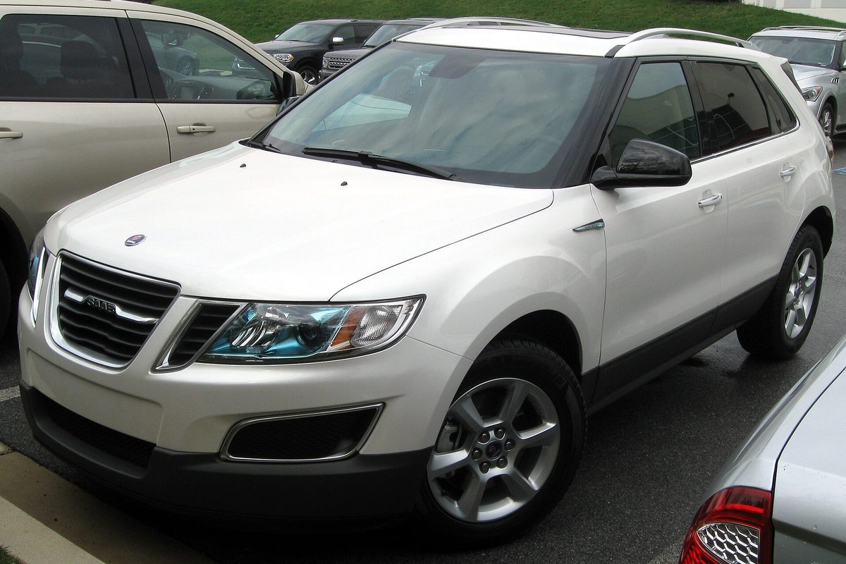 A white Saab 9-4X crossover parked in a lot between other cars, seen from the front corner