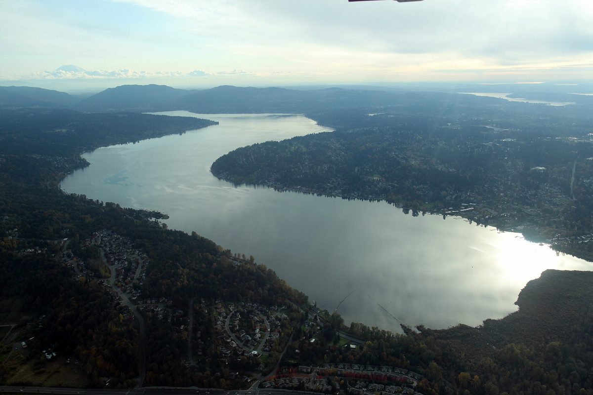 Aerial view of Lake Sammamish from its north end looking south, with forested shores, neighborhoods and hills under a hazy sky