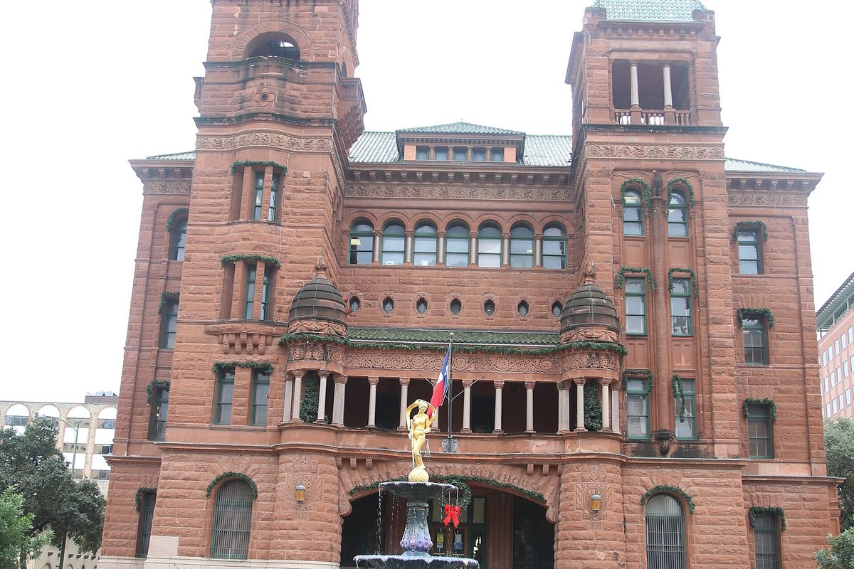 The red sandstone Bexar County Courthouse in downtown San Antonio, with twin towers, arched windows and a gilded statue atop a fountain by the entrance