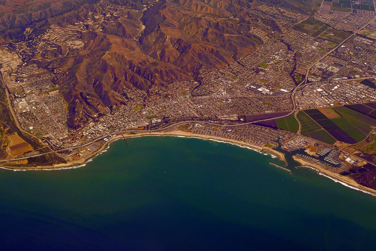 Aerial view of Ventura's coastline, with the city spread between the Pacific and brown hills and a harbor at the right edge