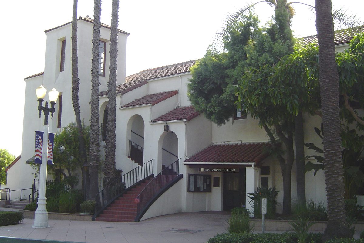 San Gabriel City Hall, a white mission-style building with a red tile roof, arched stairways and tall palm trees