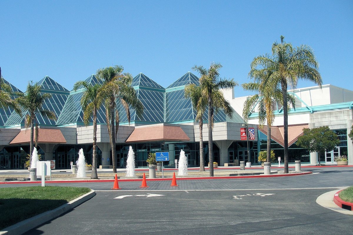 The Santa Clara Convention Center, with green glass pyramid roofs, palm trees and fountains out front, under a clear blue sky