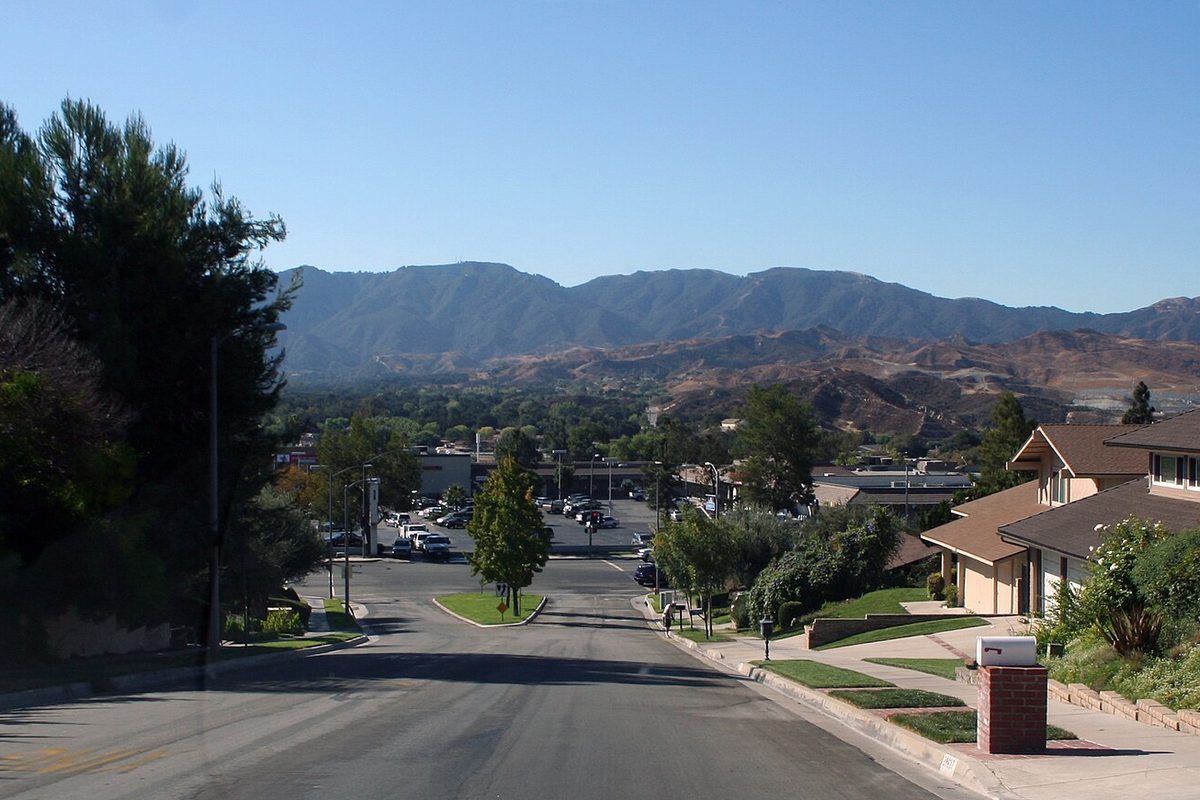 A residential street in Canyon Country, Santa Clarita, sloping down to an intersection with dry brown mountains beyond and a brick mailbox in front