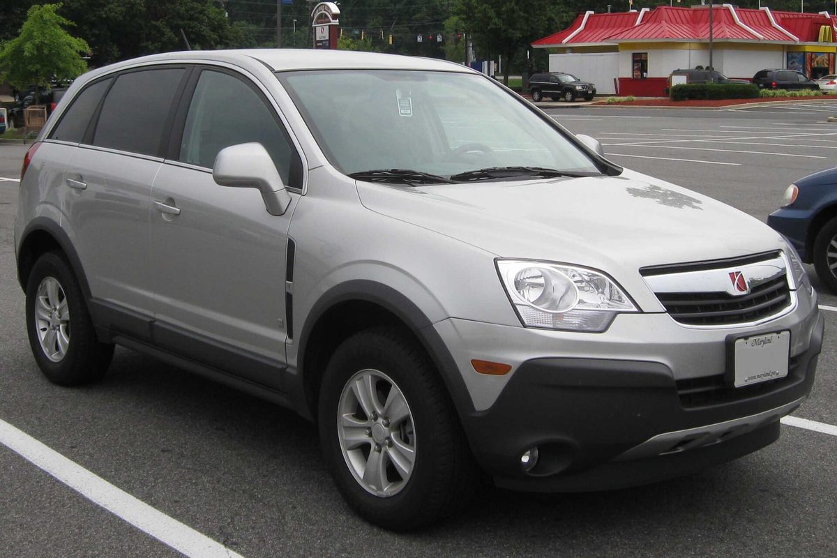 A silver 2008 Saturn Vue crossover parked in a lot in front of a building with a red roof