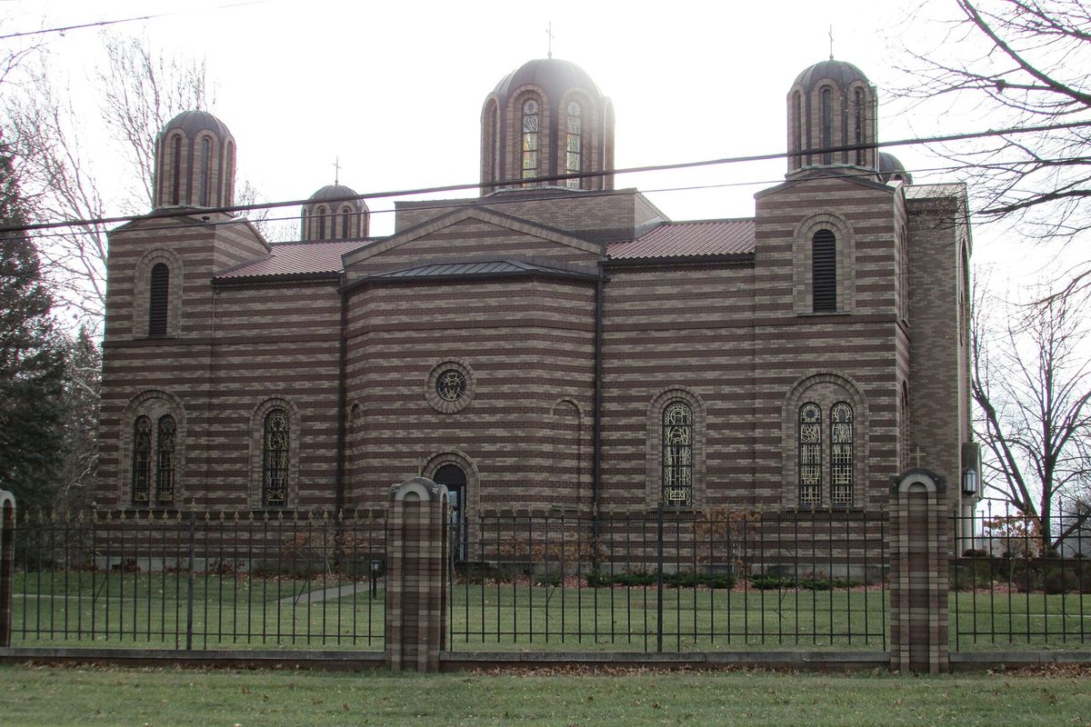 St. George Serbian Orthodox Church in Schererville, a striped brick church with three domed towers behind an iron fence and a lawn
