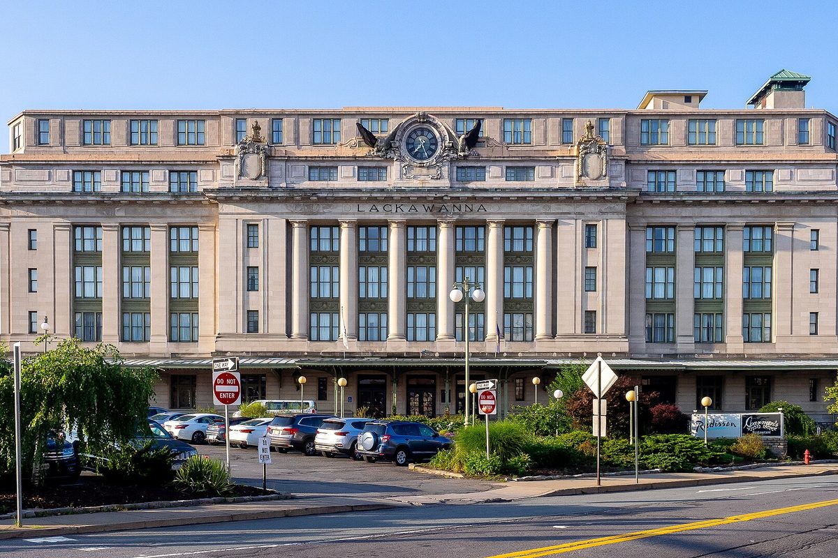 The former Lackawanna railroad station in Scranton, now a hotel, with a large clock and eagle carving above its stone columns and cars parked out front