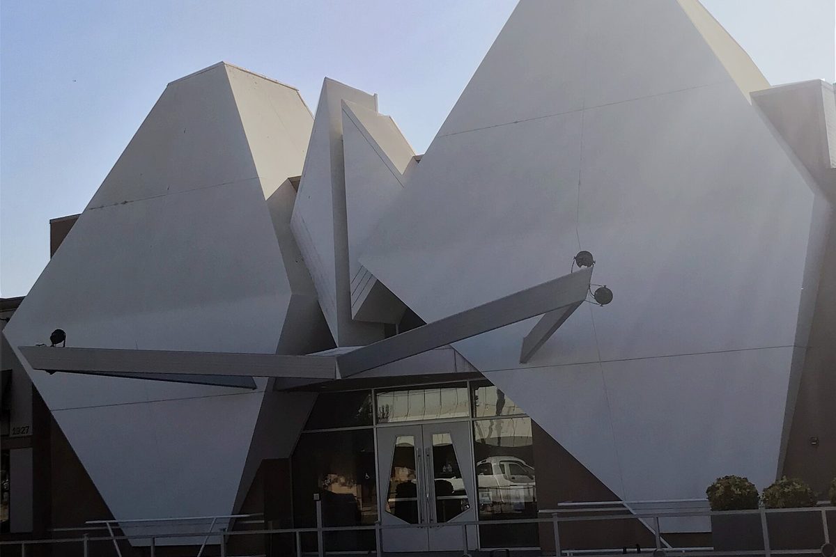 The front of the Selma Arts Center, a white building faced with large angular folded panels around a pair of glass entry doors