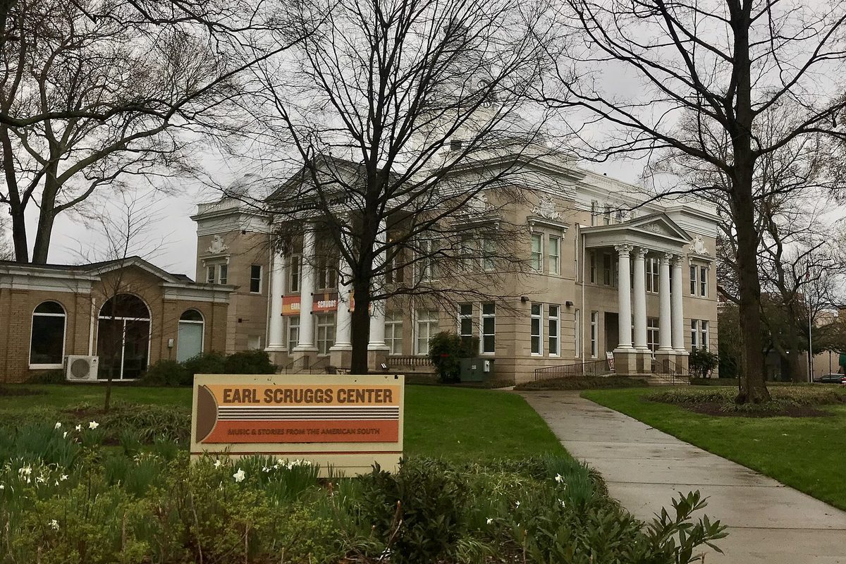 The columned former Cleveland County Courthouse, now the Earl Scruggs Center, behind bare trees with an orange Earl Scruggs Center sign on the lawn