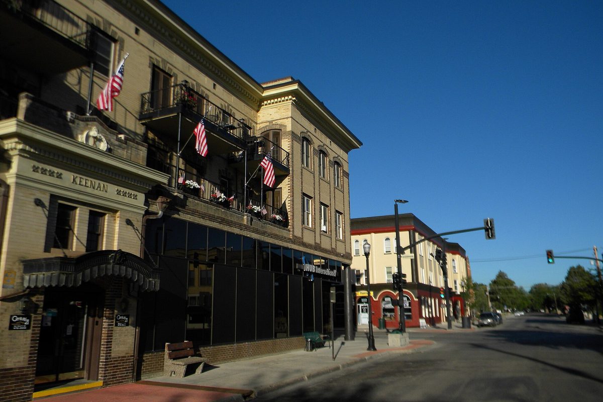 Brick and stone buildings with American flags on their balconies along Main Street in Sheridan's historic district, the Keenan building at left