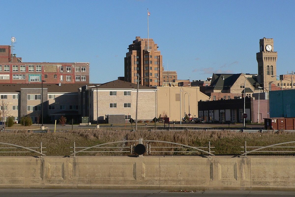 Downtown Sioux City seen from across Wesley Parkway, with the tall brick Woodbury County Courthouse and its flagpole in the middle and a clock tower on the right, under a clear blue sky