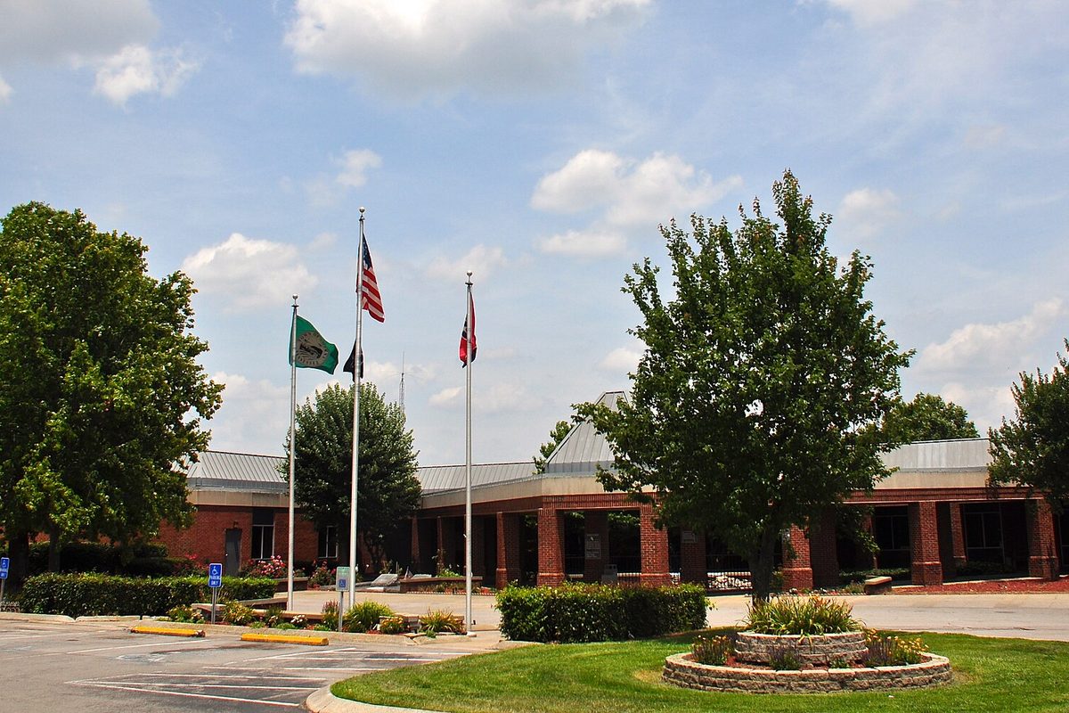 Smyrna's red-brick town hall on South Lowry Street with three flagpoles and a round stone flower bed on the lawn out front