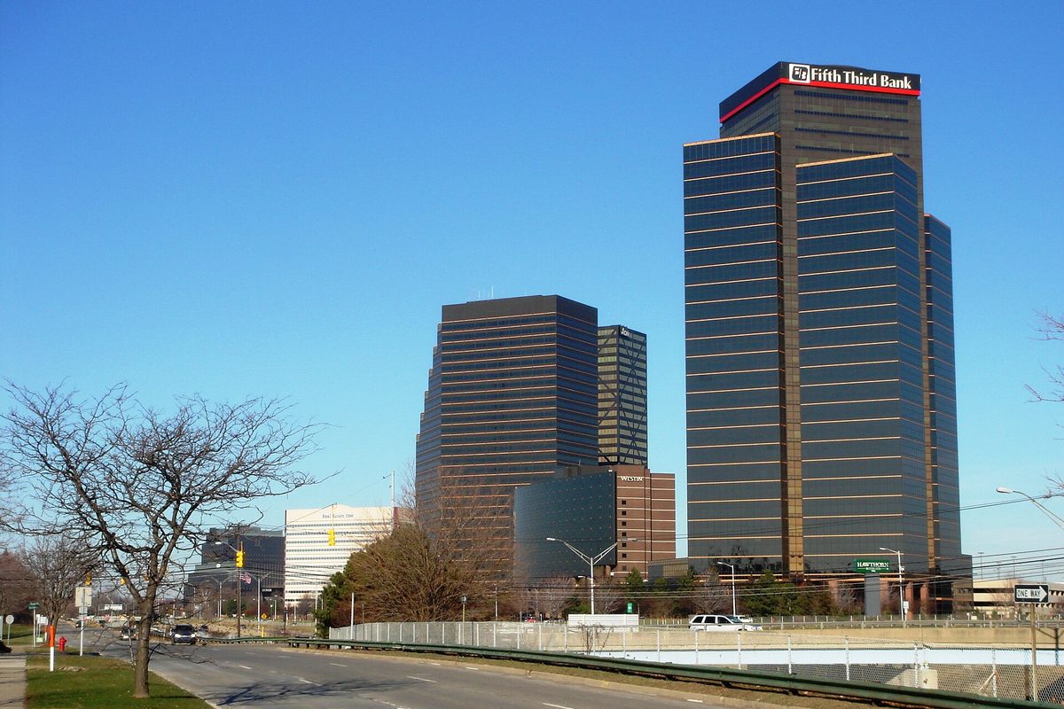 The dark glass office towers of Southfield Town Center rising beside a road lined with bare trees under a clear blue sky