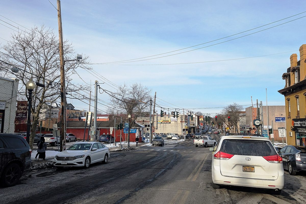 Main Street in downtown Spring Valley on a winter day, with parked cars, snow along the curb, storefronts and traffic lights ahead