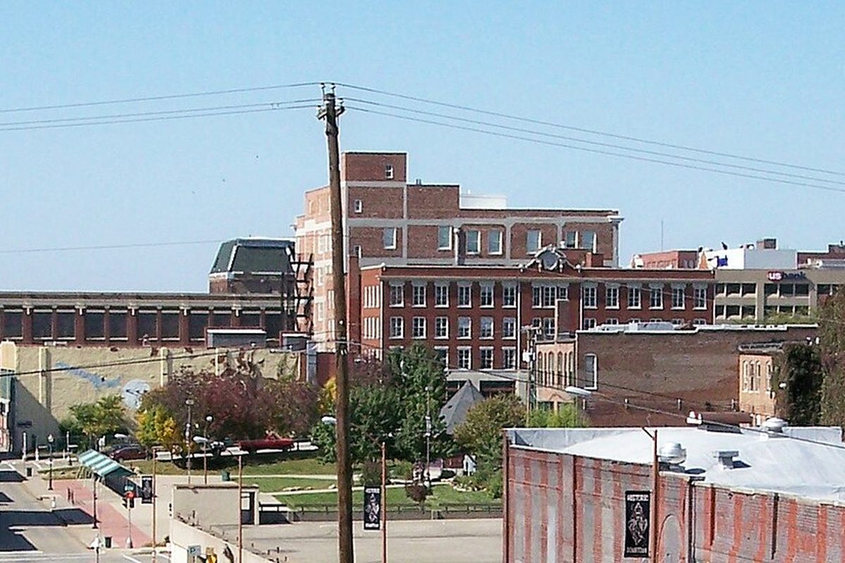 Downtown St. Joseph seen from the east: red brick buildings of several heights, a utility pole and power lines in front, under a clear blue sky