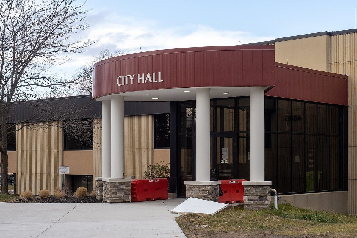 The entrance to Sterling Heights City Hall, with a curved red canopy over white columns and stone bases