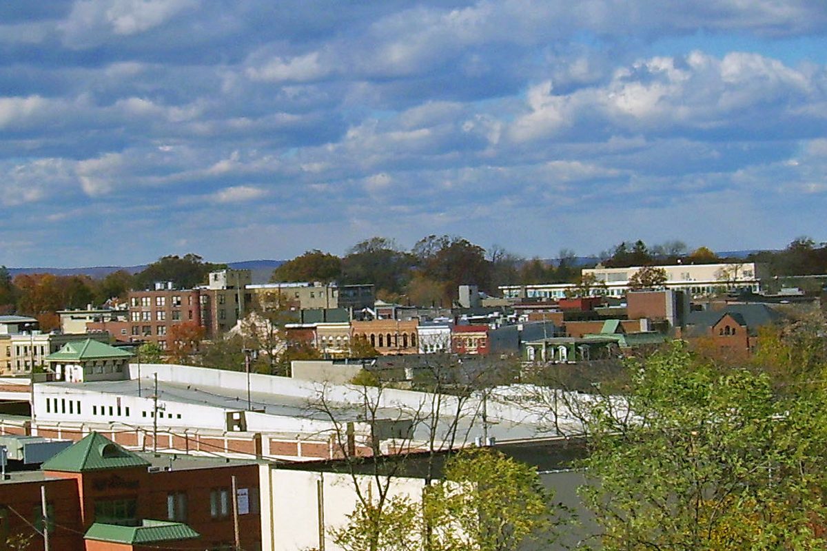 Downtown Summit seen from above, with brick buildings, green roofs and autumn trees under a blue sky full of clouds