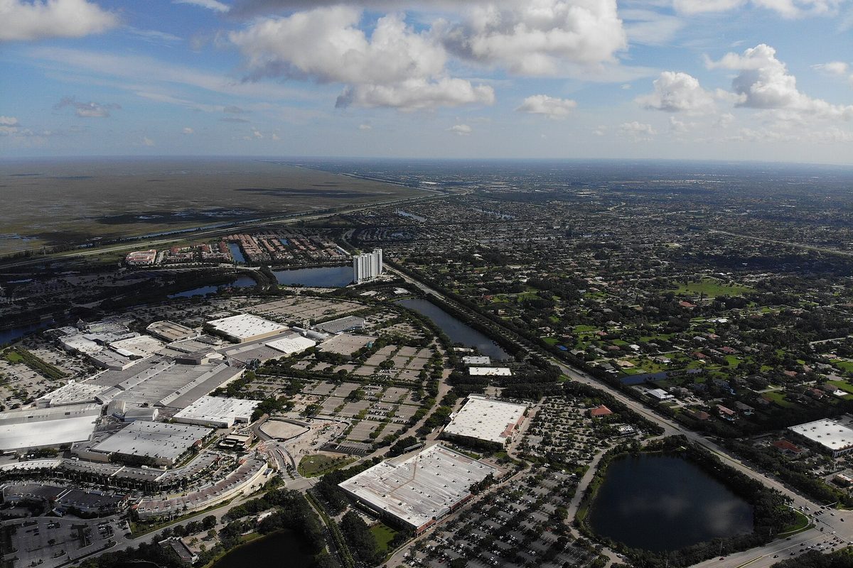 Aerial view of Sawgrass Mills mall and the neighborhoods of Sunrise, with lakes, a canal and flat open land stretching to the horizon
