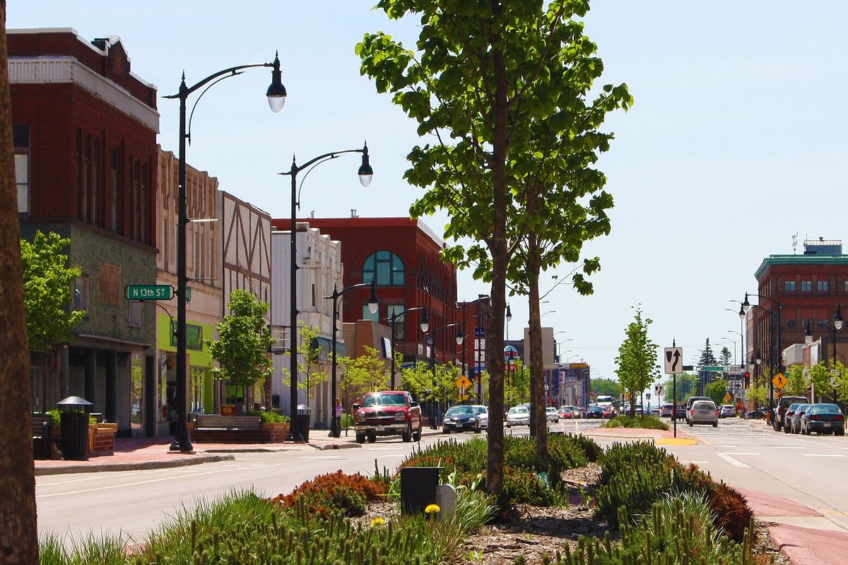Tower Avenue in downtown Superior with red brick storefronts, black street lamps and young trees in a planted median