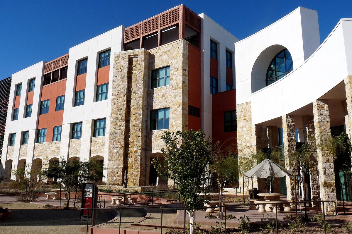 Surprise City Hall, a multi-story building of stacked stone, white walls and orange panels with an arched entrance, under a deep blue sky