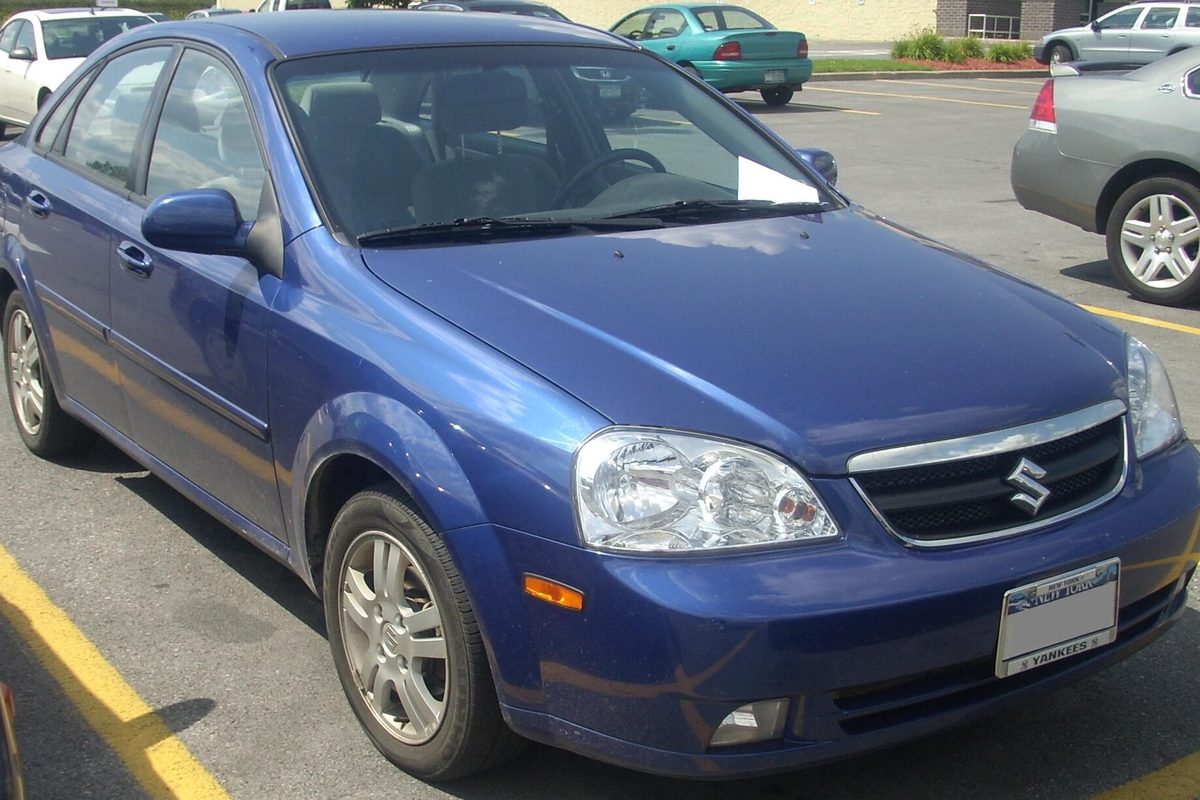A blue Suzuki Forenza sedan parked in a shopping center lot, seen from the front right