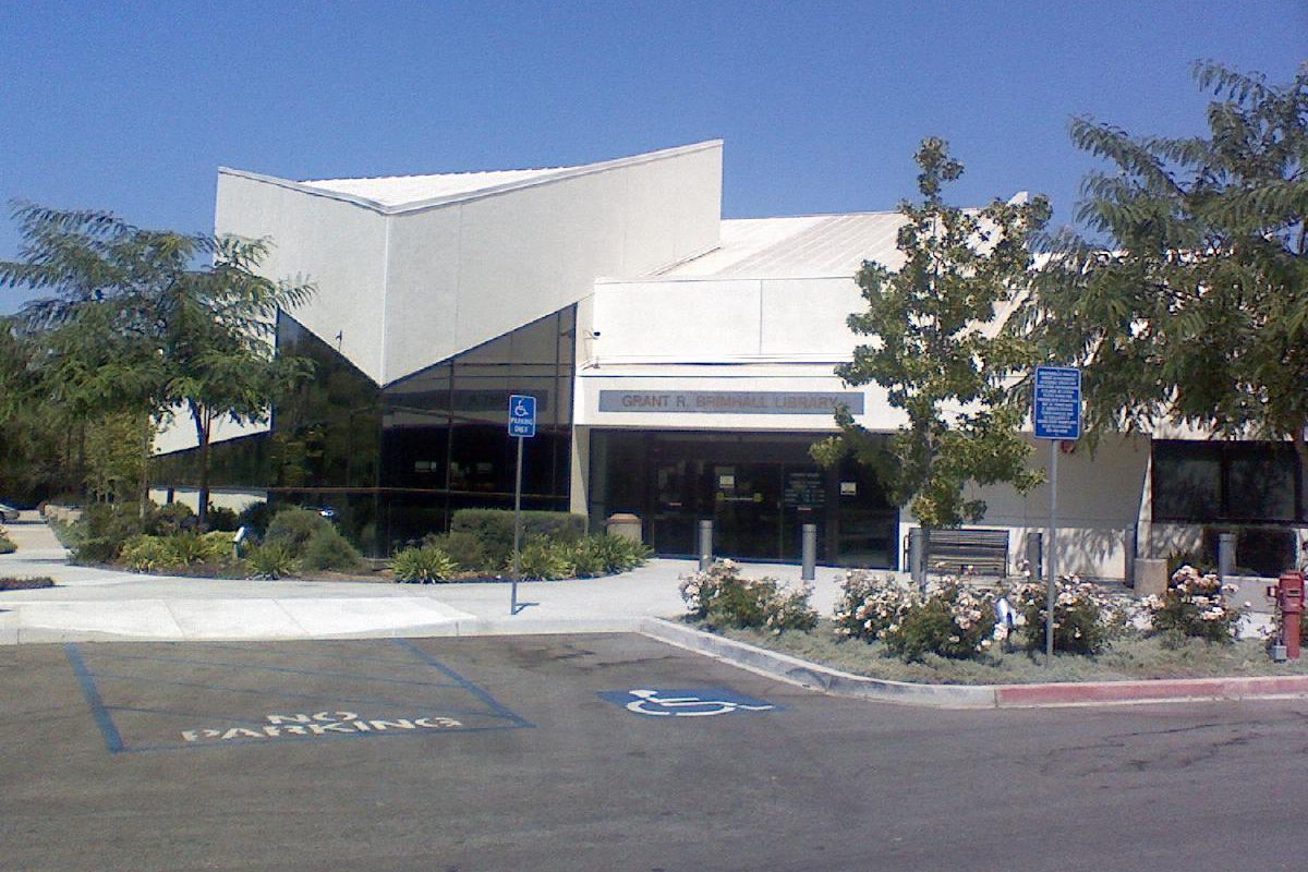 The white, angular children's wing of the Grant R. Brimhall Library in Thousand Oaks, with a parking lot, rose bushes and trees in front