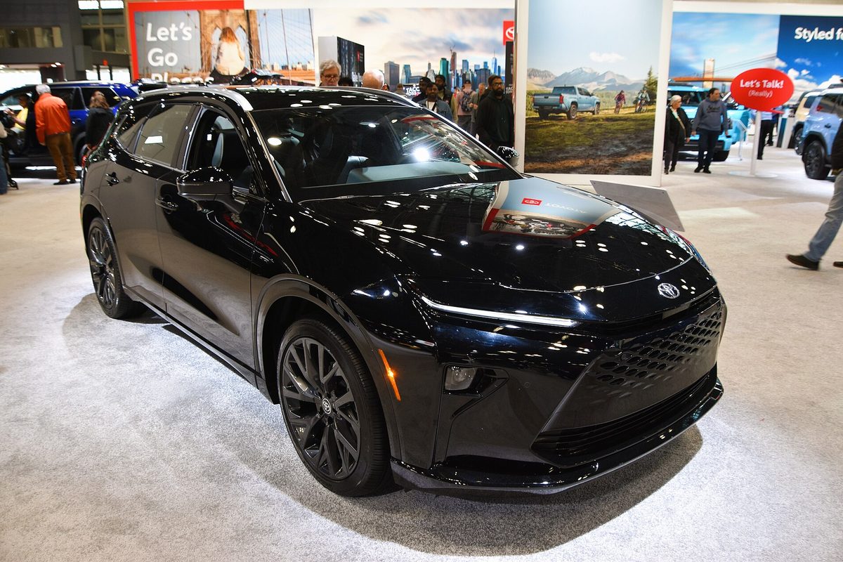 A black 2026 Toyota Crown Signia Limited on an auto show floor, with visitors and display banners behind it