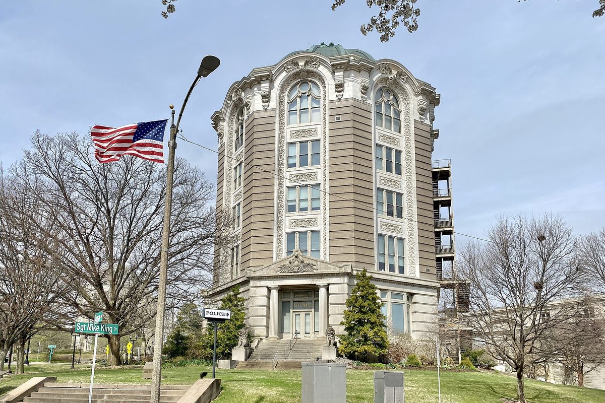 University City's City Hall, an eight-sided Beaux Arts tower with tall arched windows, with an American flag and a Sgt Mike King street sign in front
