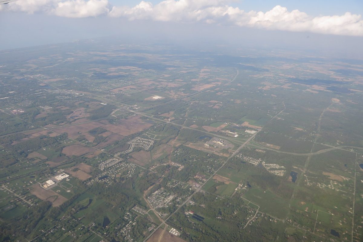 Aerial view of northwest Indiana between Valparaiso and South Bend: patchwork farm fields, roads and clusters of subdivisions under a hazy sky