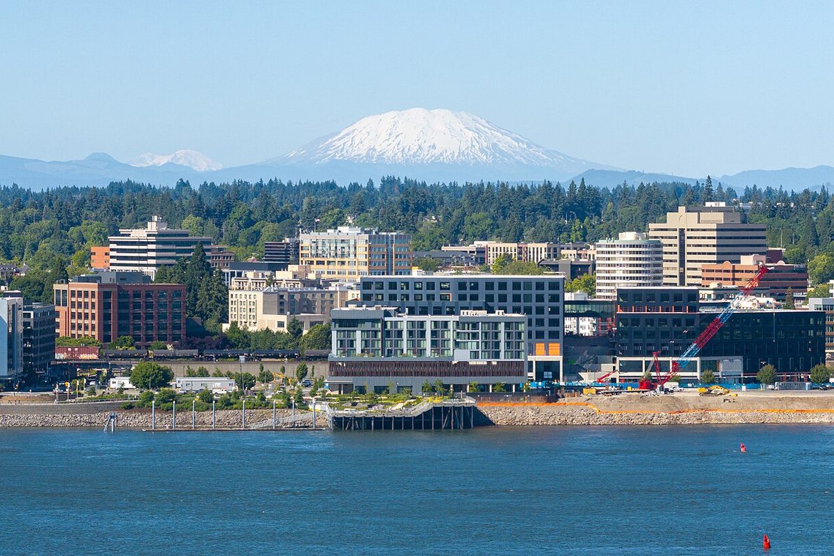 Drone view of the Vancouver waterfront with new buildings along the river, a crane and snow-capped Mount St. Helens in the distance