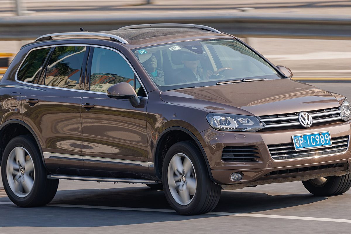 A brown second-generation Volkswagen Touareg SUV driving on a city road, the background blurred by motion