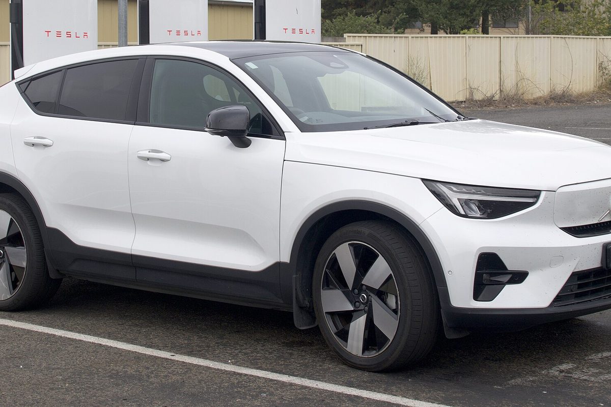 A white Volvo C40 Recharge electric SUV with a sloped roof parked at a row of EV charging stalls