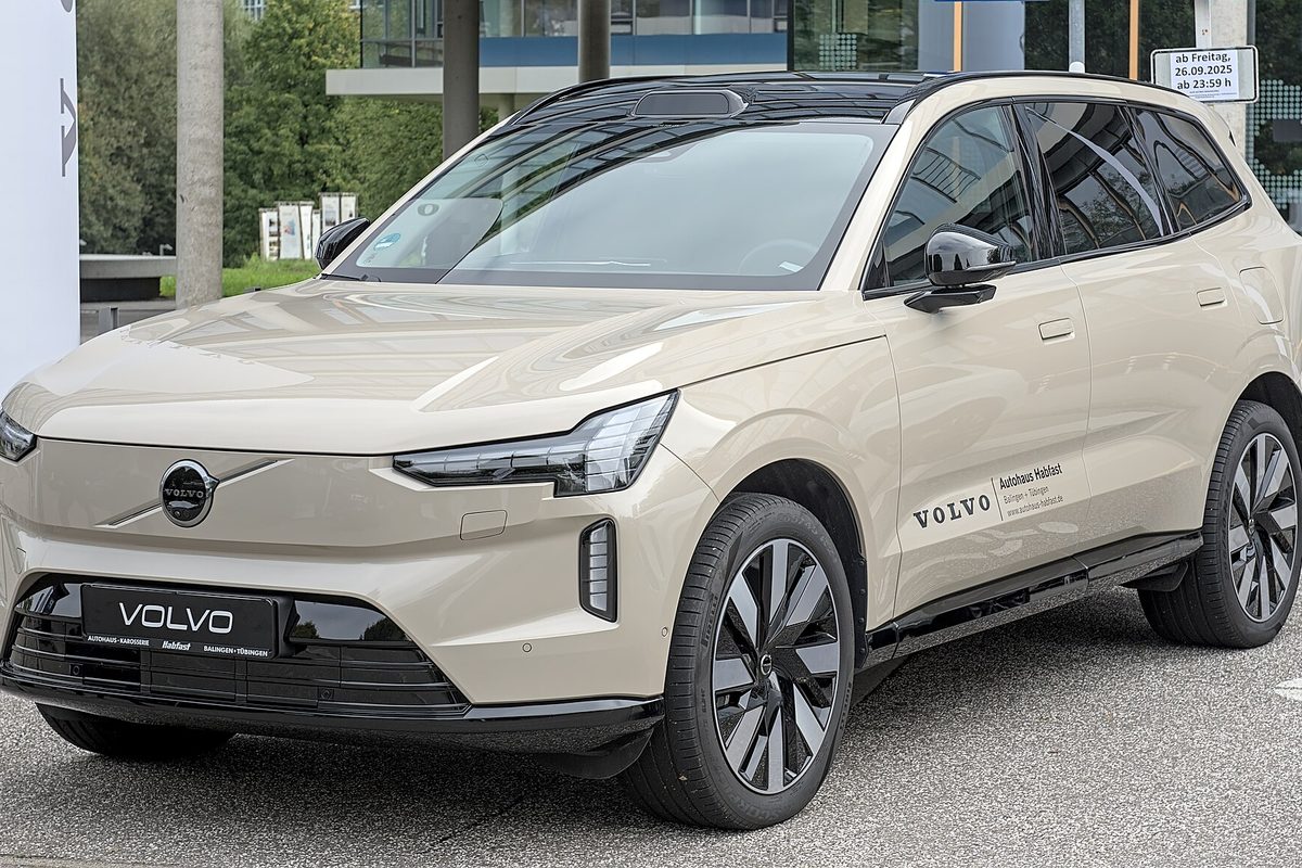 A sand-colored Volvo EX90 electric SUV parked outside a dealership