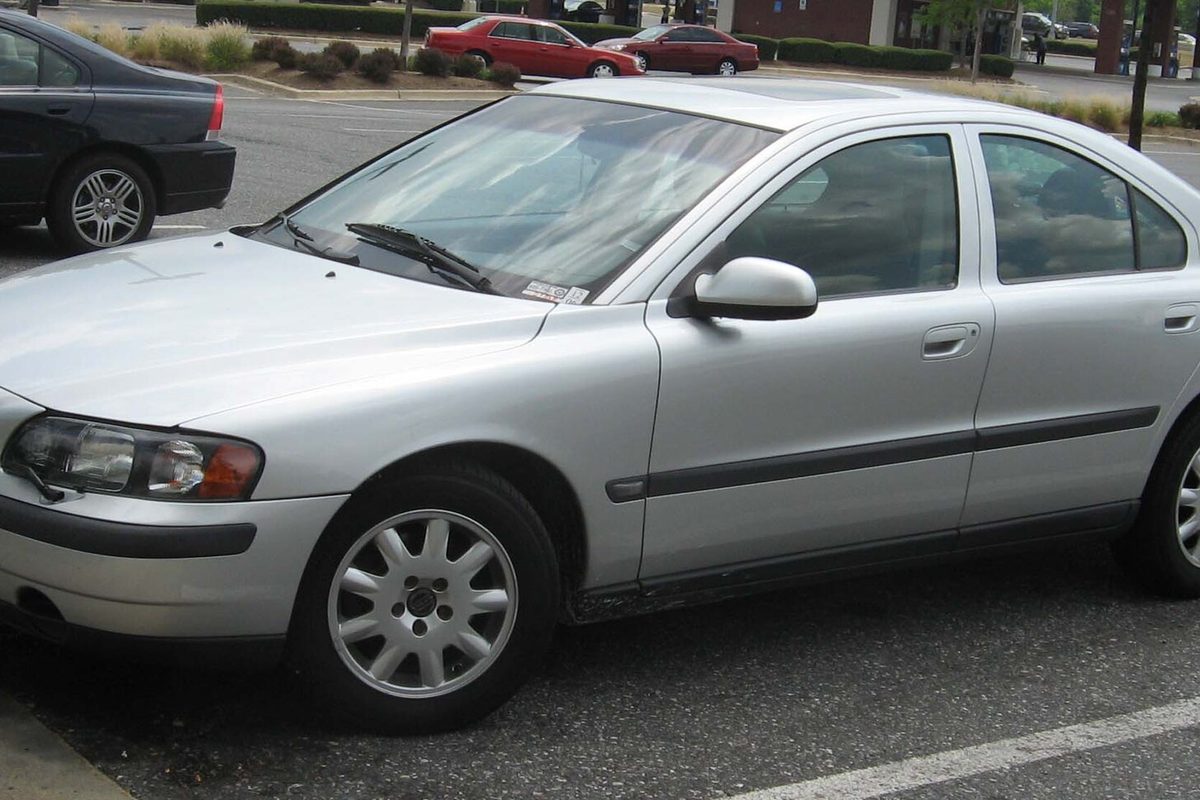 A silver first-generation Volvo S60 sedan parked in a parking lot, seen from the front left