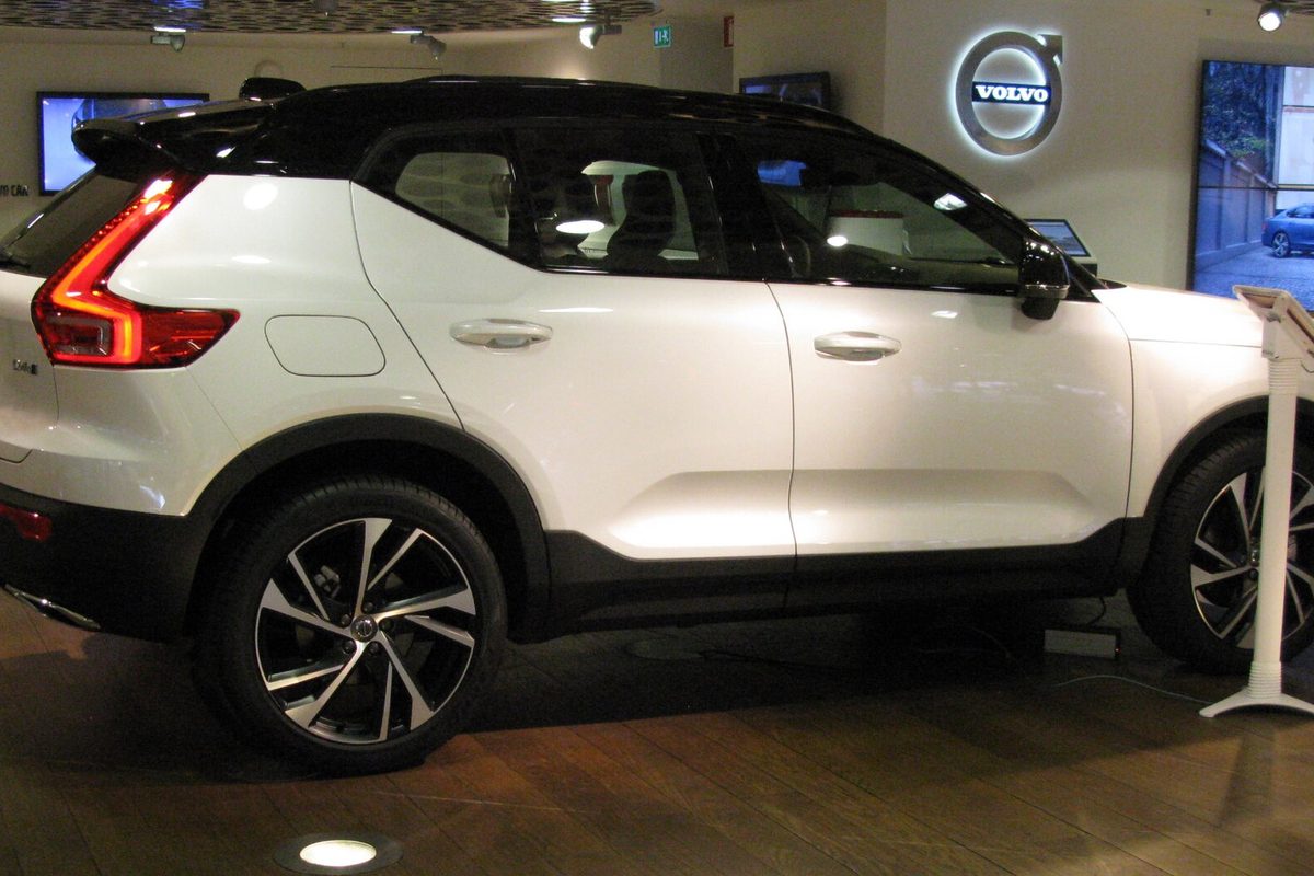 A white Volvo XC40 with a black roof and two-tone alloy wheels, seen from the side on a showroom floor