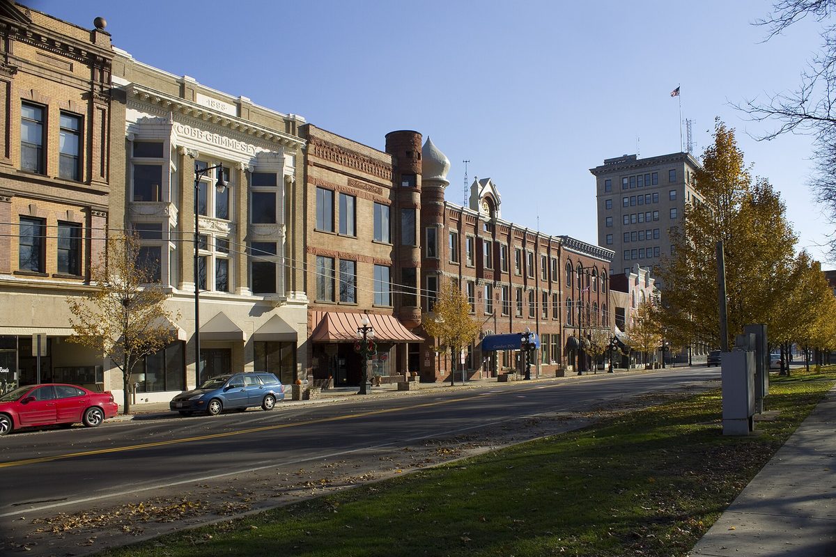 A block of historic brick and stone storefronts on Courthouse Square in downtown Warren, one with a round turret topped by a small dome, under autumn trees