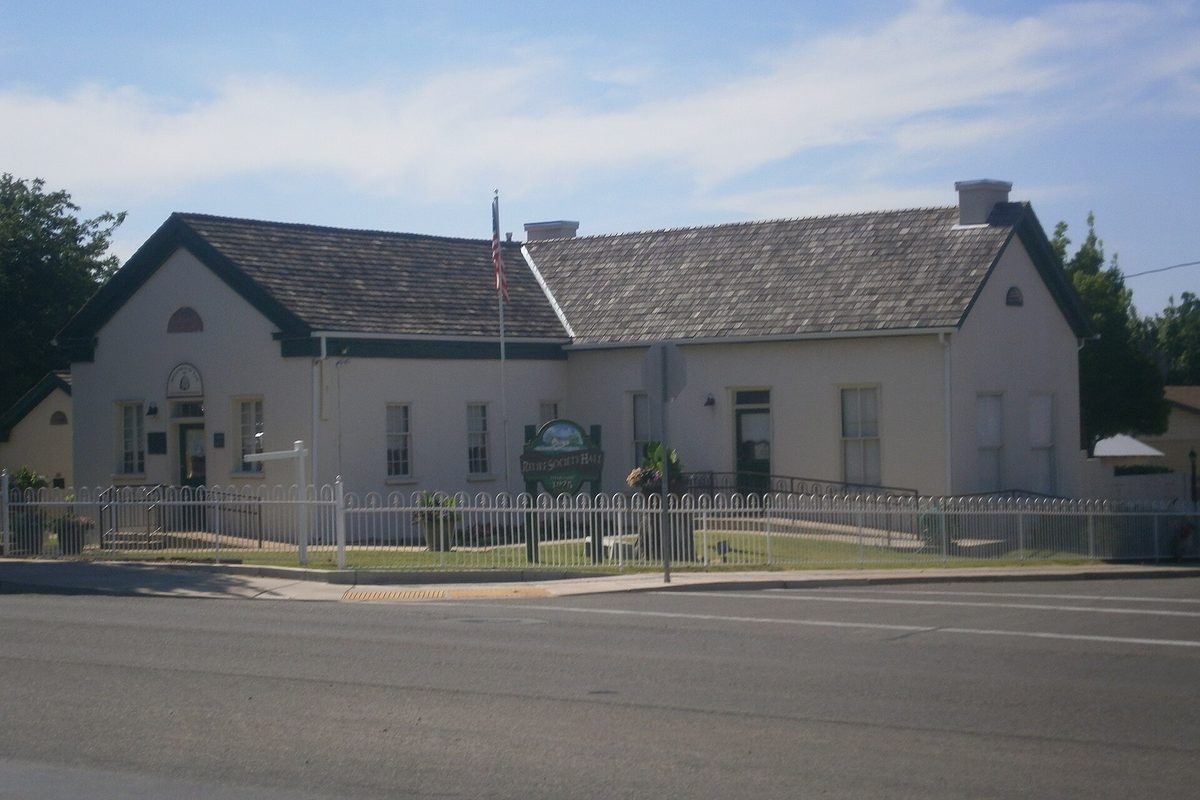 The historic Washington Relief Society Hall, a white single-story building with a gray shingle roof behind a white picket fence