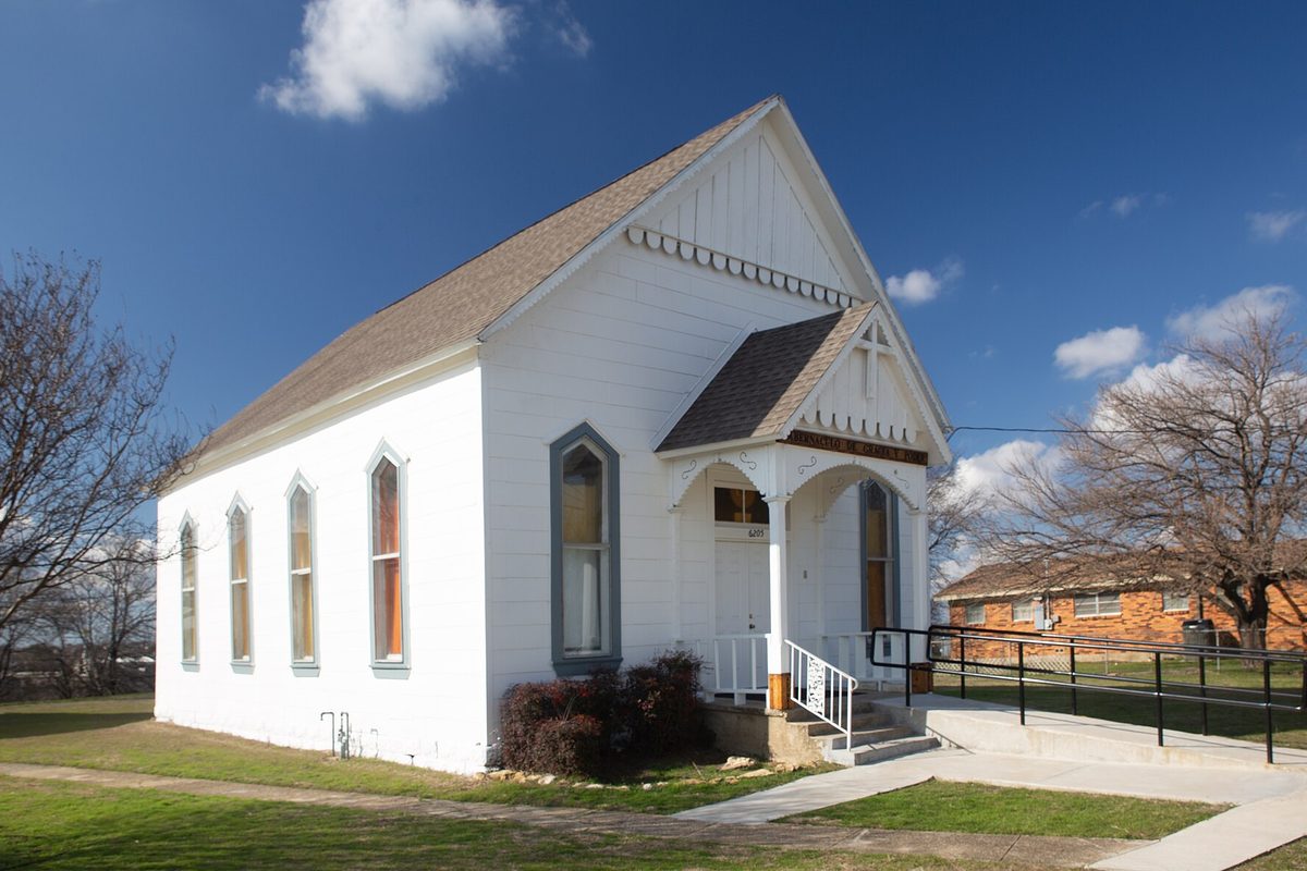 The former Watauga Presbyterian Church, a small white wooden church with tall arched windows and a gabled front porch, under a blue sky with bare trees