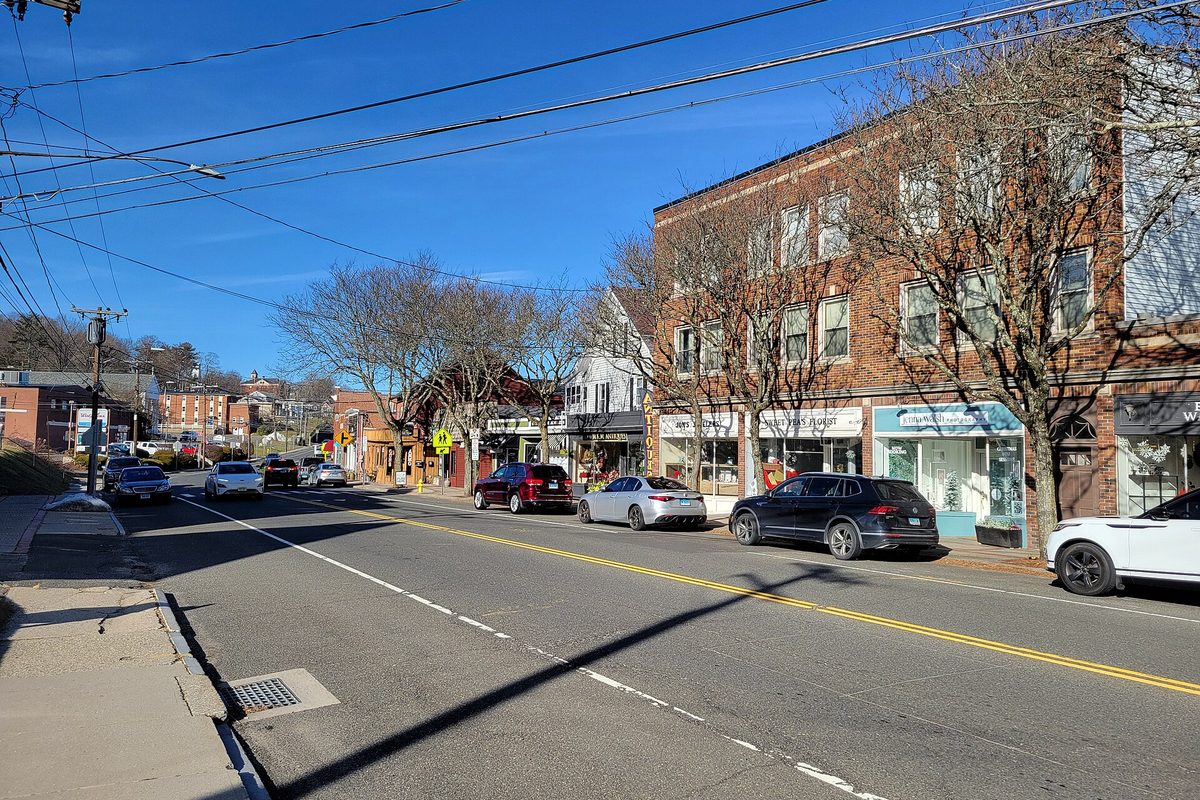 Main Street in Watertown on a sunny winter day, with cars parked along a row of brick and clapboard storefronts under bare trees