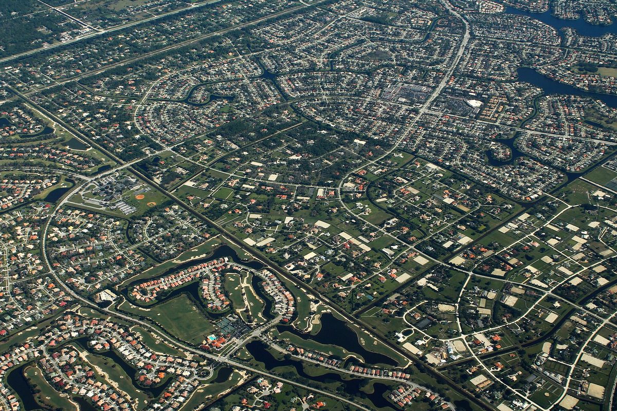 Aerial view over Wellington: curving subdivisions, large lots, ponds and a golf course crossed by long straight roads