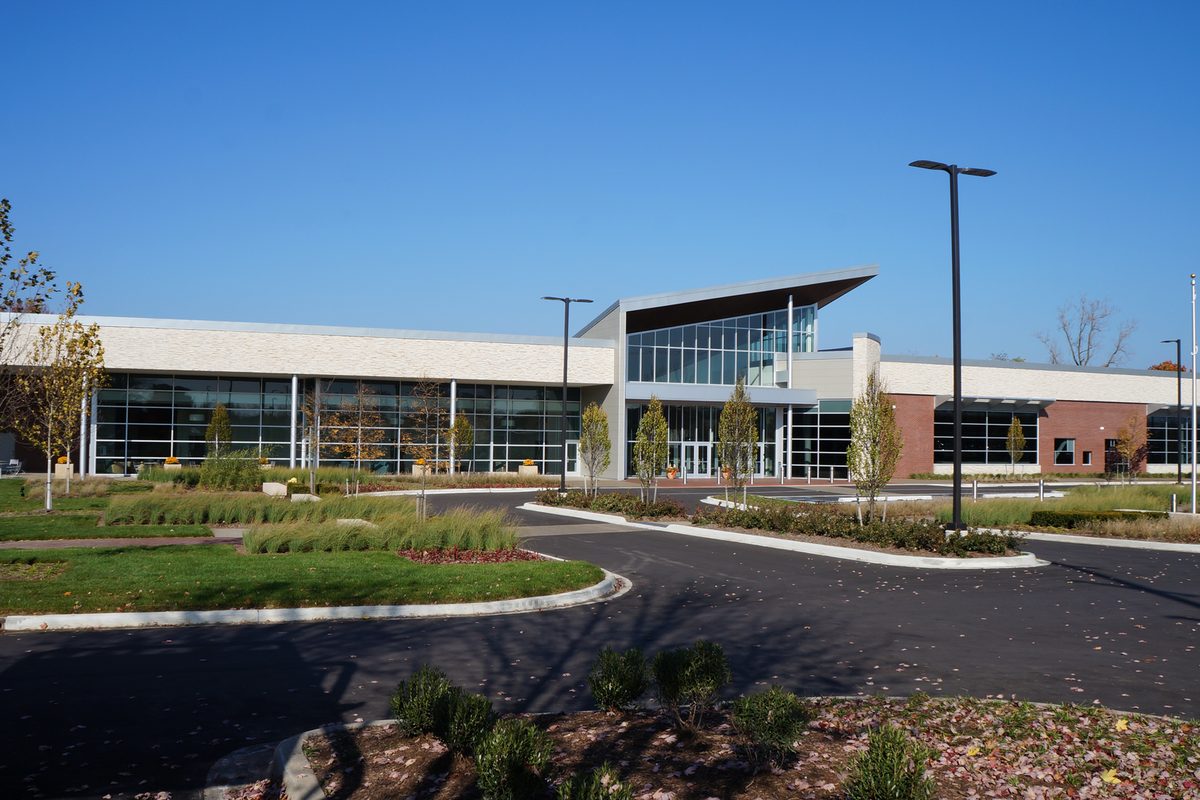 Westland City Hall, a long, low building of glass and pale stone behind a landscaped drive and lawn under a clear blue sky