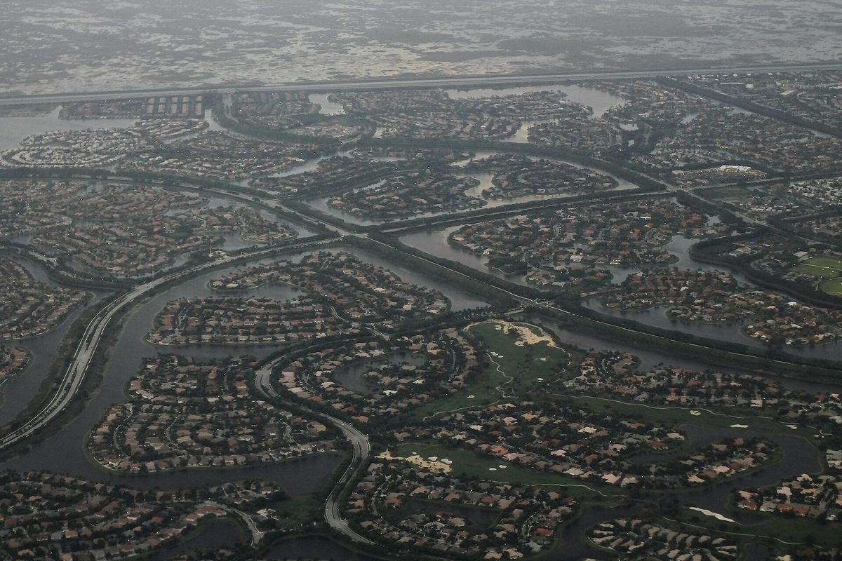 Aerial view of Weston's curving neighborhoods, each ringed by canals and lakes, under a hazy gray sky