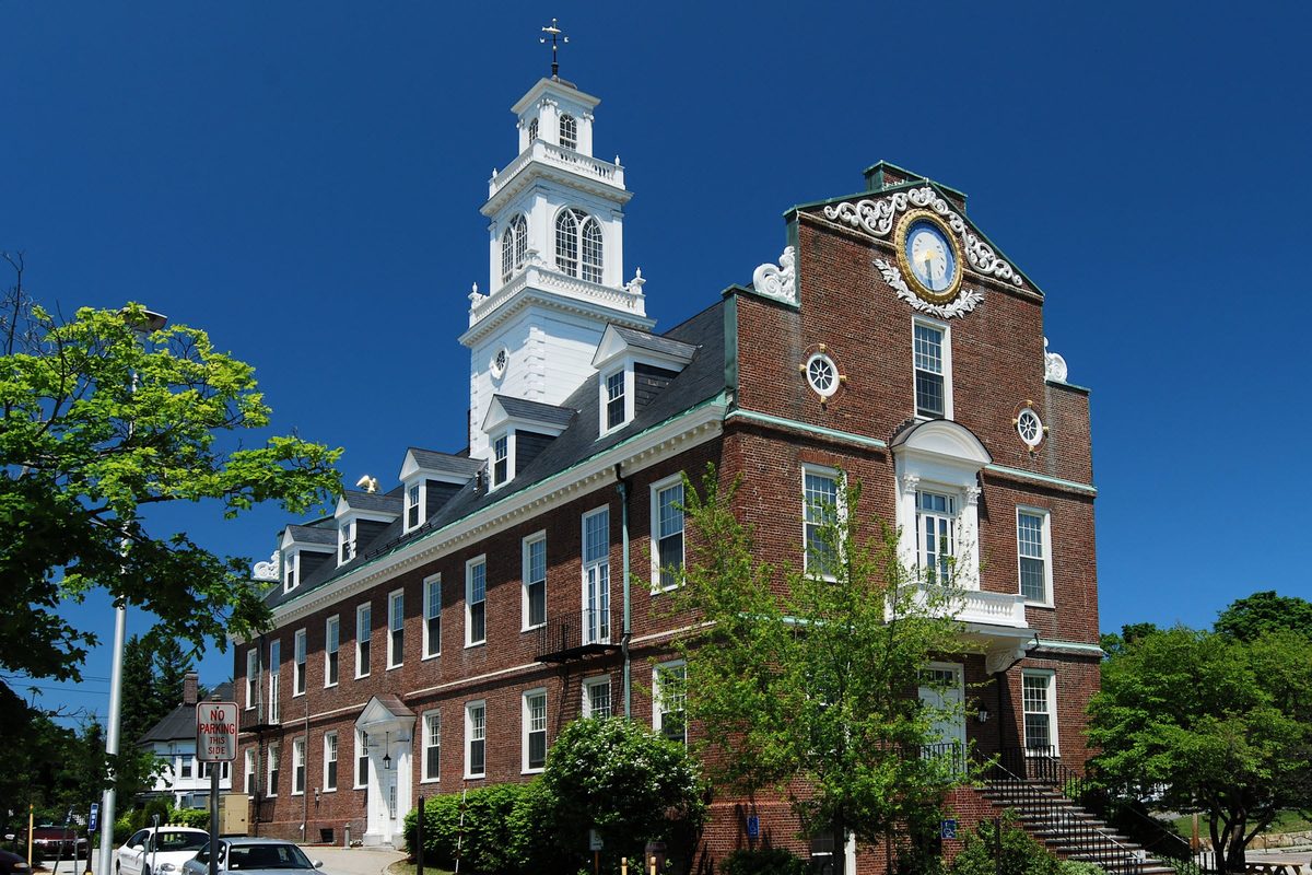 Weymouth Town Hall, a red-brick building with a white clock tower and a carved clock in its stepped gable, against a deep blue sky
