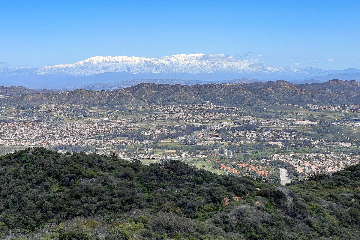 View east over the Wildomar and Murrieta valley from the brushy Santa Ana Mountains, with snow-capped peaks on the horizon