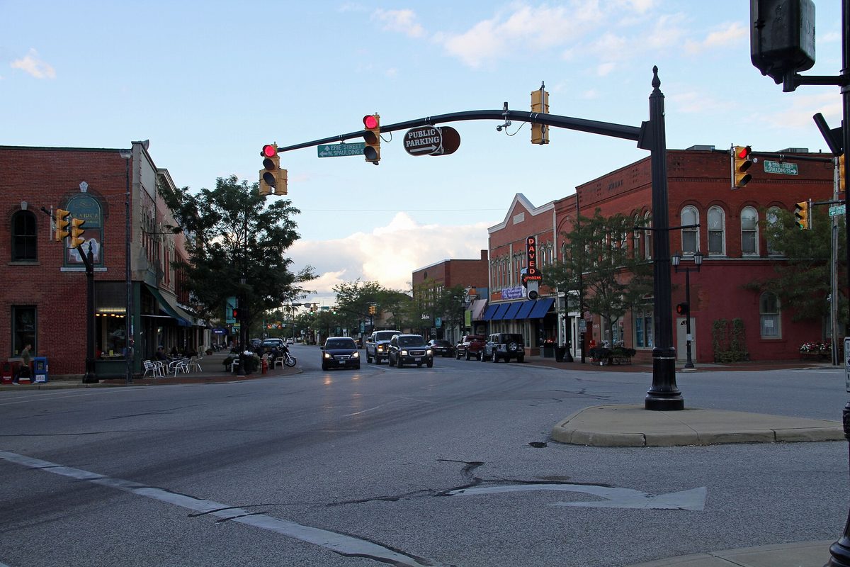 Downtown Willoughby looking east on Erie Street, with traffic lights, a Public Parking sign, two-story red-brick storefronts and cars coming toward the camera