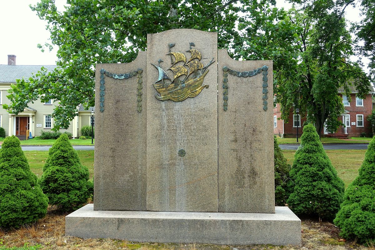 The granite Founders of Windsor Monument on Palisado Green, topped by a bronze sailing ship and flanked by trimmed evergreens
