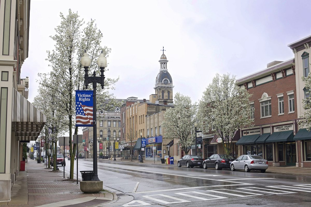 East Liberty Street in downtown Wooster on a rainy spring day, with white-blossomed trees, brick storefronts and a domed tower at the end of the street