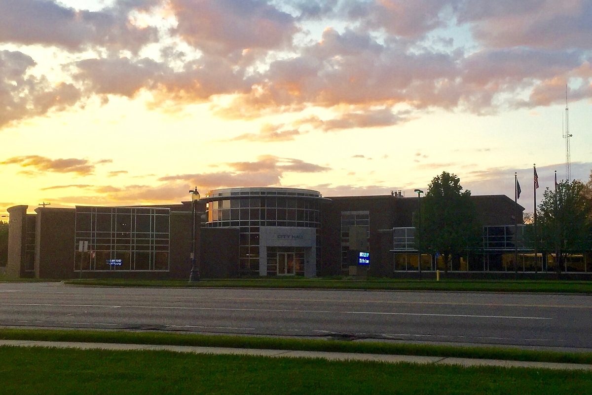 Wyoming, Michigan City Hall, a low brick and glass building with a rounded glass entry, under an orange sunset sky across a wide road